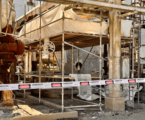 Certified technicians performing asbestos abatement with protective equipment and controlled material handling.