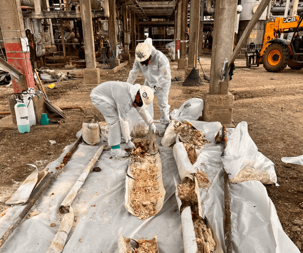 Contained asbestos abatement area with warning signage and controlled access inside an industrial facility.