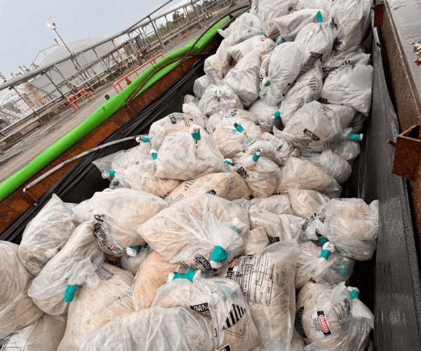 Worker removing asbestos-containing material using wet methods and protective gear during abatement work.