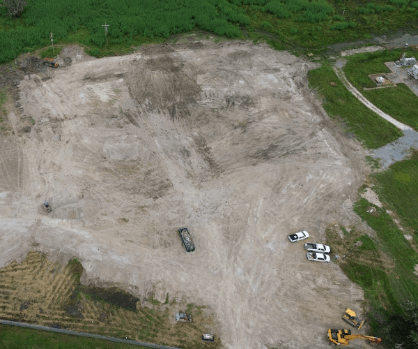 Excavator dismantling concrete foundations and infrastructure as part of controlled industrial decommissioning.