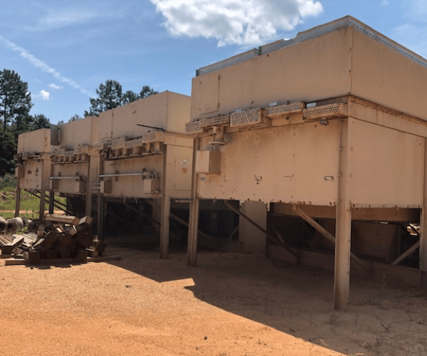 Large industrial processing units awaiting dismantling and material recycling at a controlled recovery site.