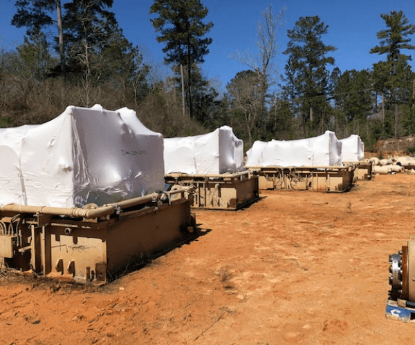 Wrapped industrial equipment staged for material recycling and asset recovery at an outdoor industrial site.
